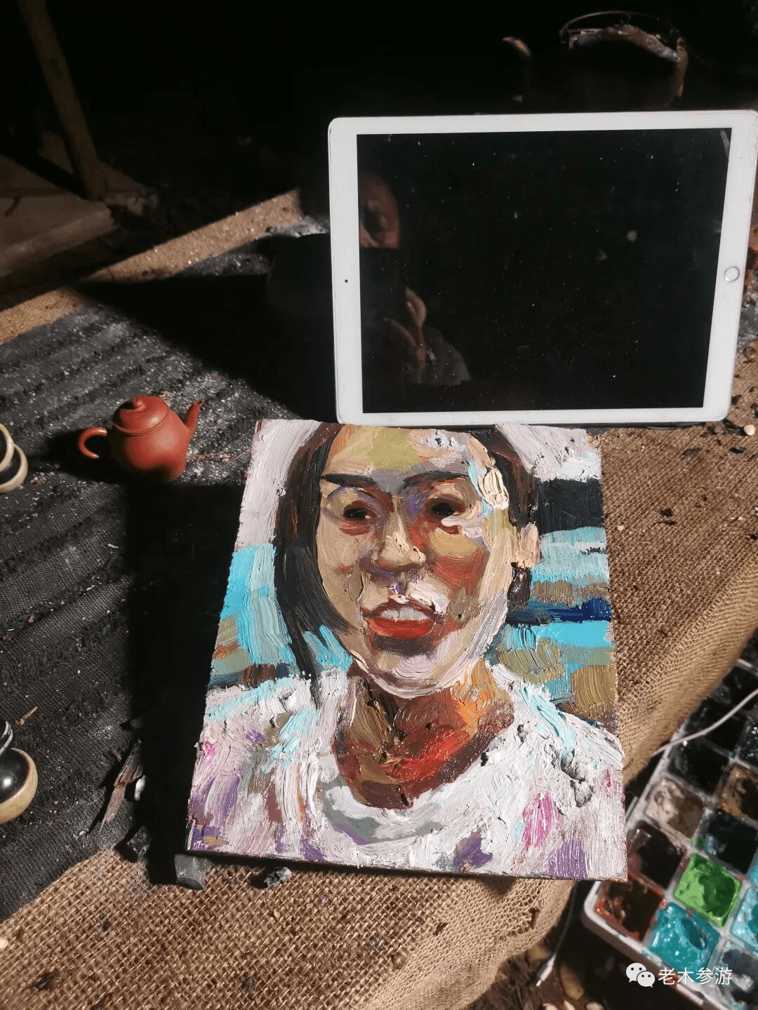 A completed arhat portrait in oil — painted from a video call, with the live subject visible on the iPad